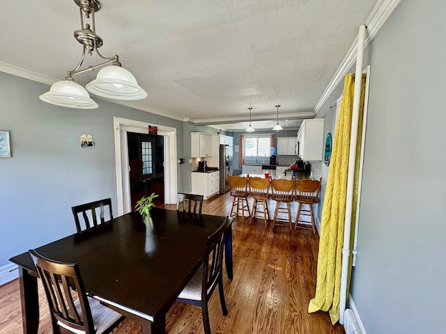 dining room with dark wood-type flooring and crown molding