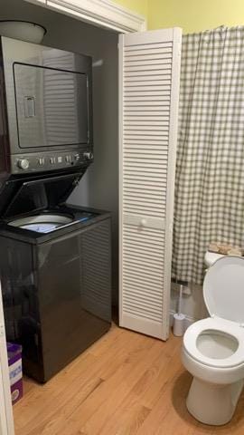 laundry area featuring stacked washing machine and dryer and light wood-style floors