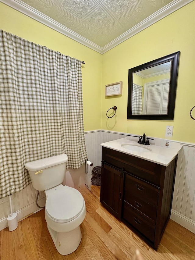 bathroom featuring wood finished floors, wainscoting, toilet, and vanity