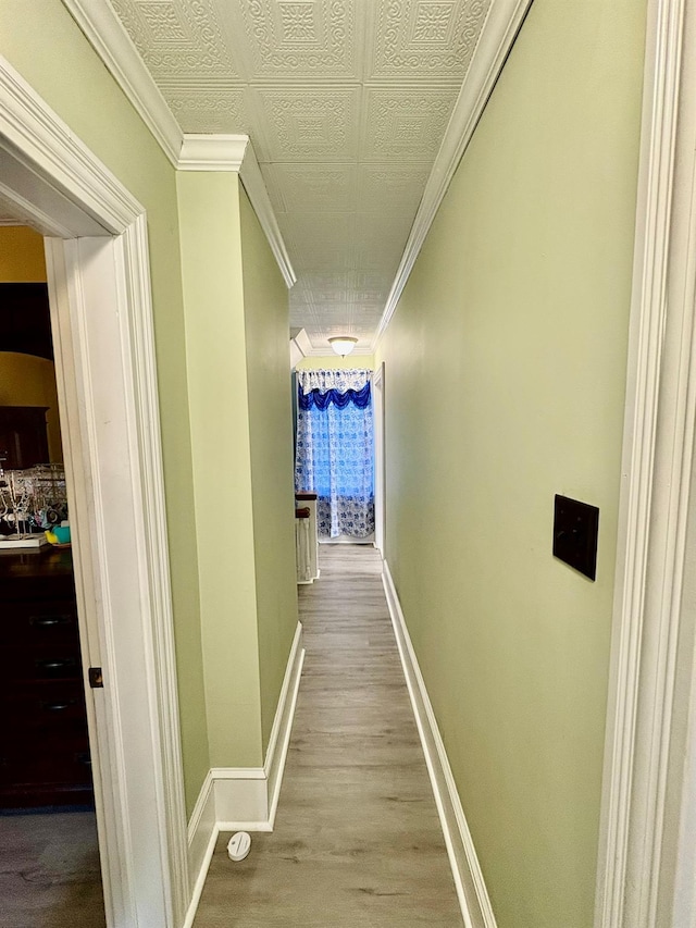 hall featuring wood finished floors, baseboards, and ornamental molding