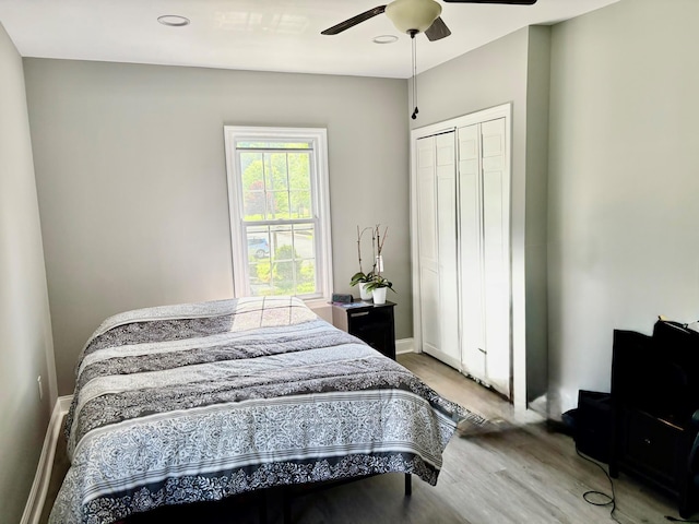 bedroom featuring wood finished floors, a closet, a ceiling fan, and baseboards