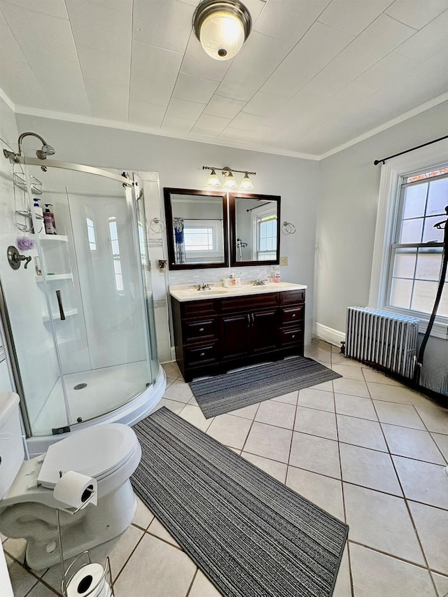 bathroom with a shower stall, double vanity, tile patterned flooring, healthy amount of natural light, and ornamental molding