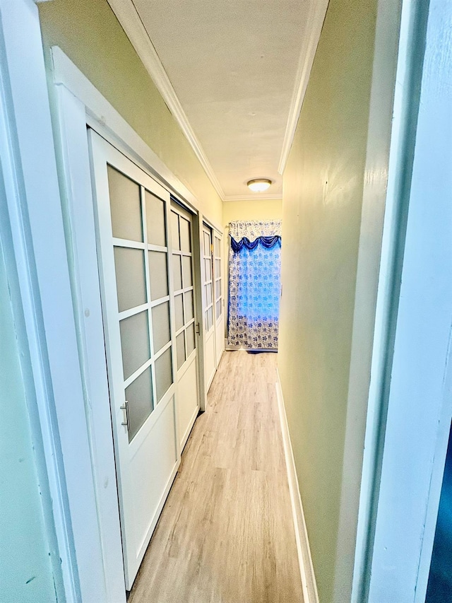 hall with crown molding, light wood-style flooring, and baseboards