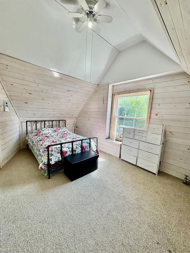 bedroom with wooden walls, carpet flooring, vaulted ceiling, and a ceiling fan