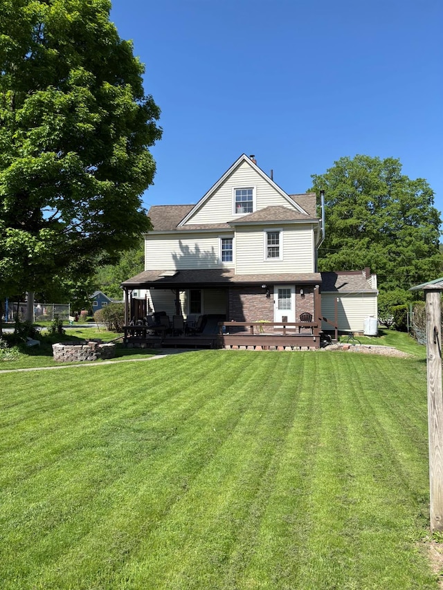 rear view of house featuring a lawn, a deck, and brick siding