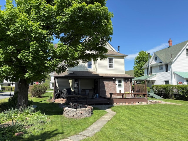 back of property featuring a lawn, a wooden deck, and brick siding