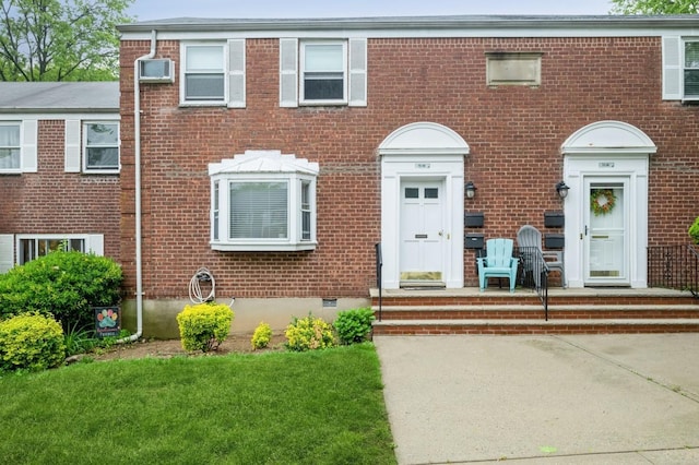 70-08 261th St Unit A1, Glen Oaks, NY 11004 - view of front of property with brick siding, a wall mounted AC, a front lawn, and crawl space