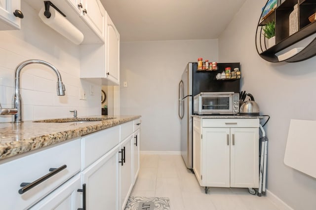 70-08 261th St Unit A1, Glen Oaks, NY 11004 - kitchen with a sink, white cabinetry, light stone countertops, decorative backsplash, and freestanding refrigerator