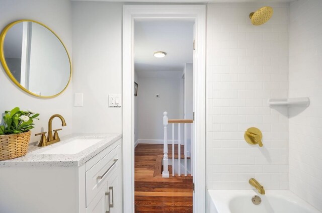 bathroom with wood finished floors, vanity, bathtub / shower combination, and baseboards