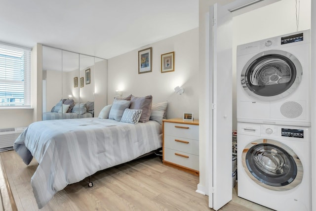 259 Dune Rd Unit 128, Westhampton Beach, NY 11978 - bedroom with estacked washer and dryer, light wood finished floors, and a closet