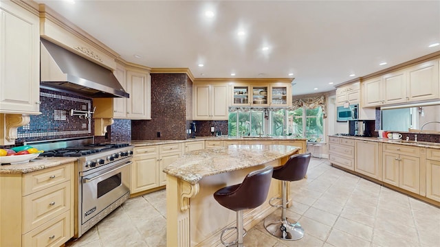 202 Broadway, Lawrence, NY 11559 - kitchen with appliances with stainless steel finishes, wall chimney exhaust hood, a kitchen bar, backsplash, and recessed lighting