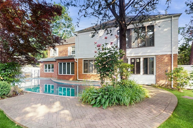 202 Broadway, Lawrence, NY 11559 - rear view of property with brick siding, an outdoor pool, and a patio area