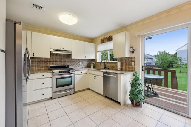 22 Knightsbridge Ct, Nanuet, NY 10954 - kitchen with stainless steel appliances, under cabinet range hood, a sink, decorative backsplash, and light stone counters