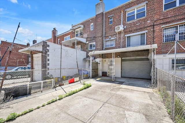 148-35 58th Ave, Flushing, NY 11355 - rear view of property with brick siding, fence, a wall mounted air conditioner, an attached garage, and a chimney