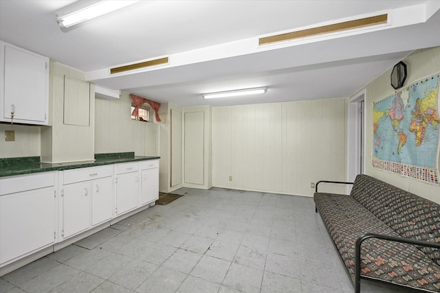148-35 58th Ave, Flushing, NY 11355 - kitchen with dark countertops, light flooring, white cabinets, and wooden walls