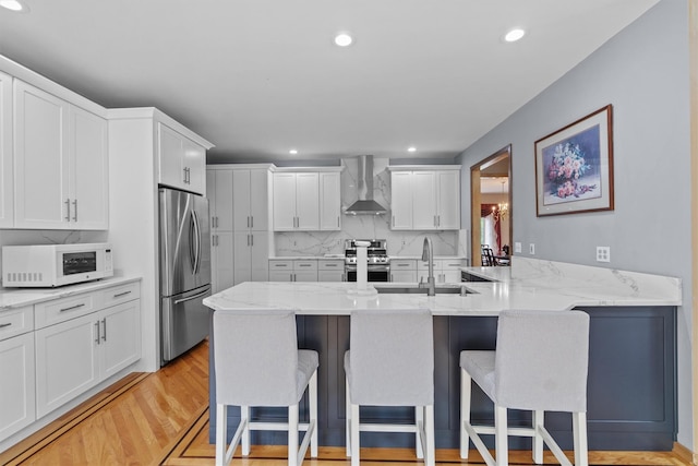 115 Moffat Rd, Washingtonville, NY 10992 - kitchen with appliances with stainless steel finishes, wall chimney range hood, a sink, a breakfast bar area, and recessed lighting