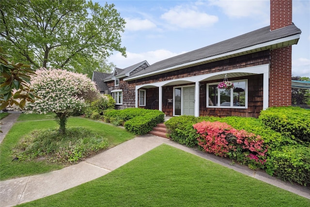 9 Lakeland Ave, Patchogue, NY 11772 - view of front facade featuring a chimney, a front yard, covered porch, and roof with shingles