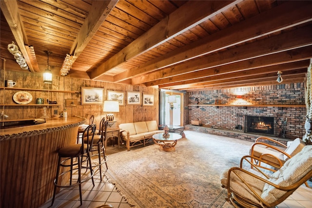 9 Lakeland Ave, Patchogue, NY 11772 - living room featuring a dry bar, wooden ceiling with exposed beams, wood walls, a brick fireplace, and tile patterned floors