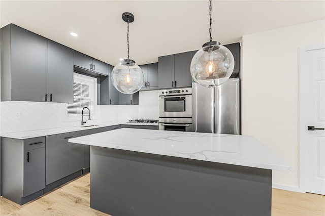kitchen with stainless steel appliances, a sink, tasteful backsplash, light wood-style floors, and gray cabinetry