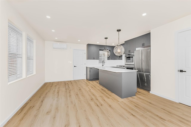 kitchen featuring freestanding refrigerator, light countertops, a wall mounted AC, gray cabinets, and light wood-style flooring