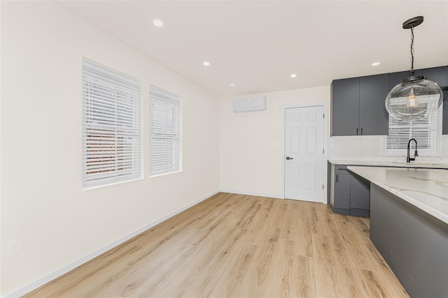 kitchen featuring a sink, a wall mounted air conditioner, light wood-style floors, hanging light fixtures, and recessed lighting