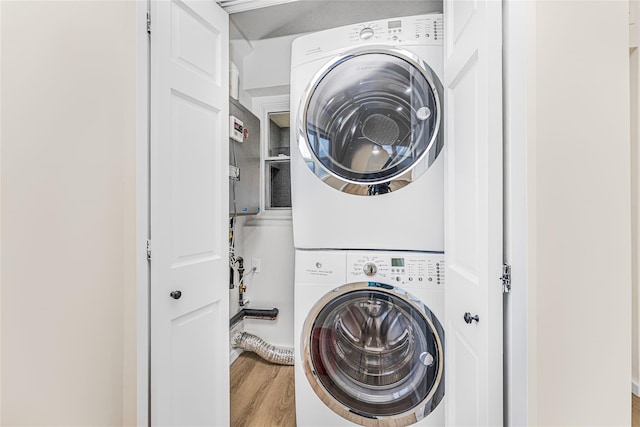 washroom with stacked washing machine and dryer and wood finished floors