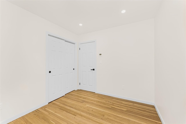 unfurnished bedroom with light wood-style flooring, baseboards, recessed lighting, and a closet