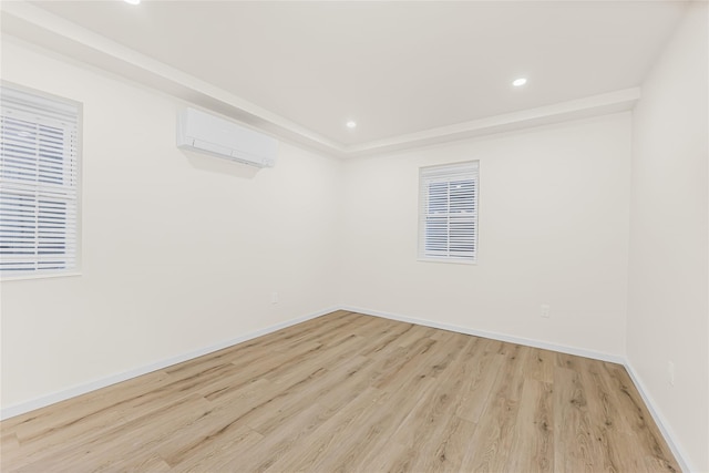 unfurnished room featuring an AC wall unit, light wood-type flooring, baseboards, and recessed lighting