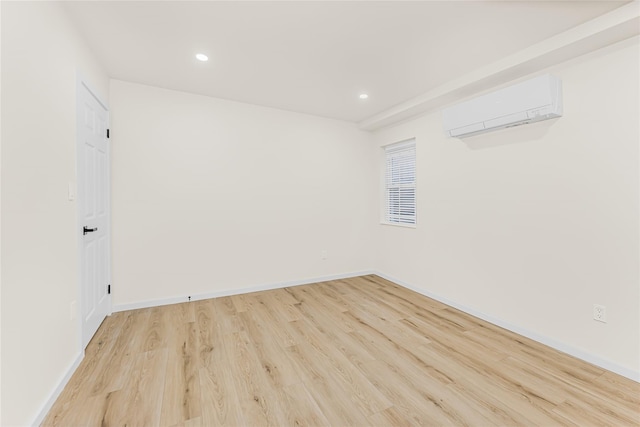 empty room with a wall mounted AC, light wood-style floors, recessed lighting, and baseboards