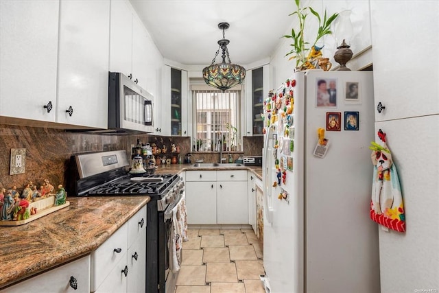 kitchen with stainless steel appliances, decorative backsplash, white cabinets, a sink, and glass insert cabinets