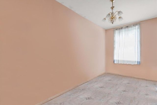 empty room with a chandelier and baseboards