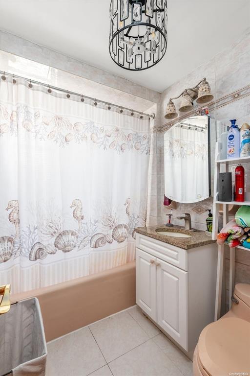 full bathroom with toilet, tile patterned floors, shower / bathtub combination with curtain, vanity, and a chandelier