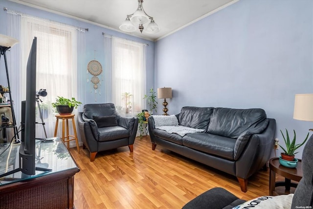 living area featuring ornamental molding, light wood-style floors, and a chandelier