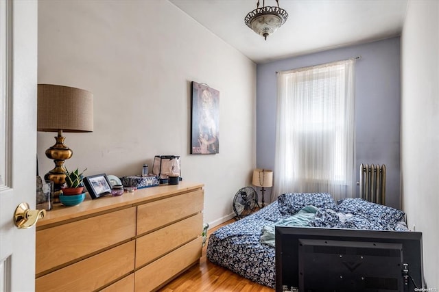bedroom featuring radiator, light wood-type flooring, and baseboards