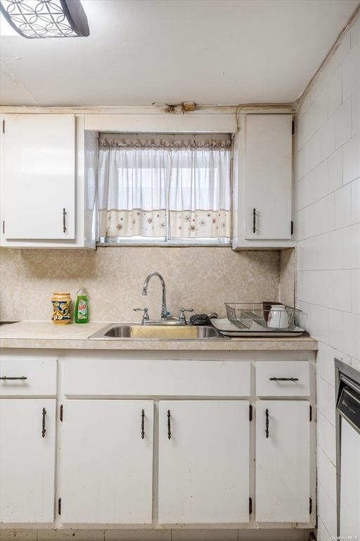 kitchen featuring a sink, light countertops, white cabinets, and tasteful backsplash