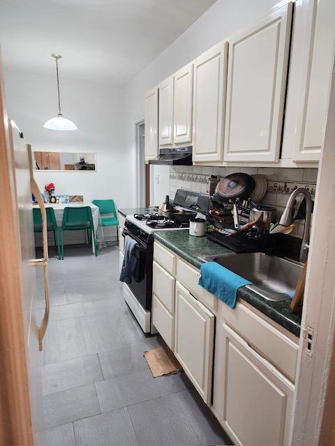 35-27 81st St Unit 2, Jackson Heights, NY 11372 - kitchen featuring gas range, decorative backsplash, white cabinetry, dark countertops, and range hood