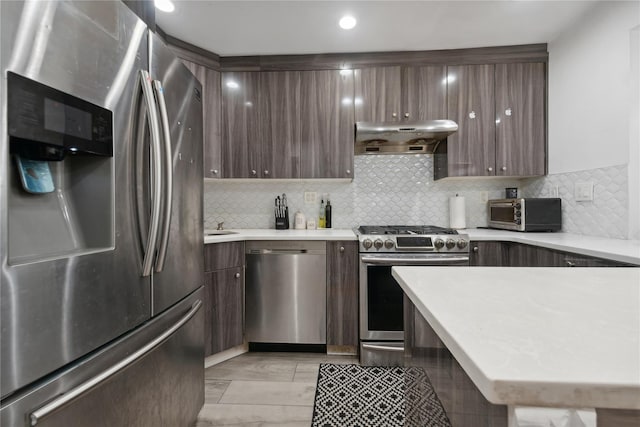 61-31 136th St, Flushing, NY 11367 - kitchen with appliances with stainless steel finishes, under cabinet range hood, light countertops, dark brown cabinets, and recessed lighting