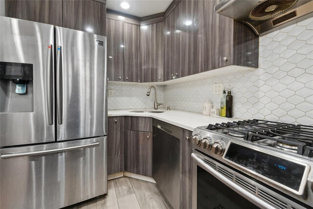 61-31 136th St, Flushing, NY 11367 - kitchen featuring appliances with stainless steel finishes, ventilation hood, dark brown cabinetry, light countertops, and tasteful backsplash