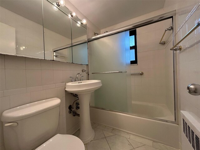 8 W Mill Dr Unit 1B, Great Neck, NY 11021 - full bathroom featuring toilet, radiator heating unit, bath / shower combo with glass door, tile patterned floors, and backsplash
