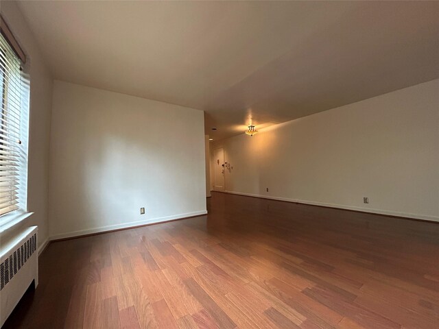 8 W Mill Dr Unit 1B, Great Neck, NY 11021 - empty room featuring wood finished floors, radiator heating unit, baseboards, and healthy amount of natural light