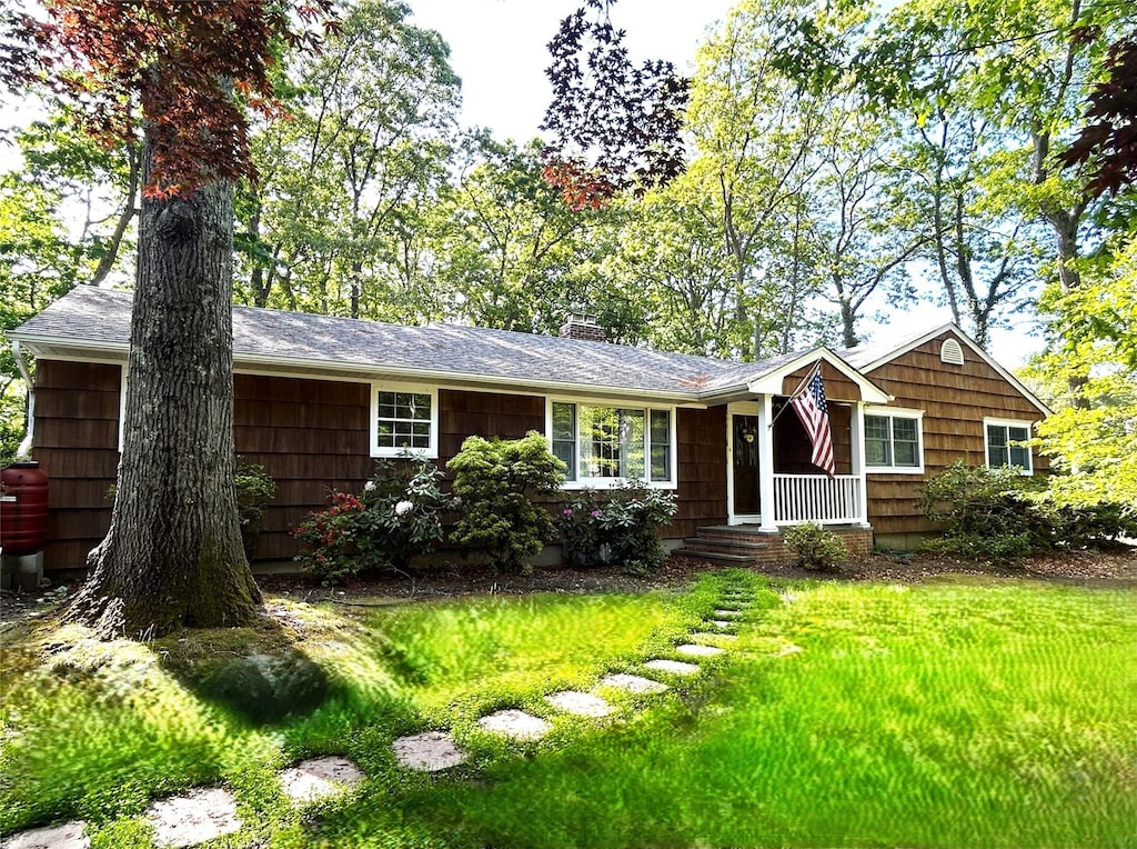 ranch-style home with a chimney and a front yard