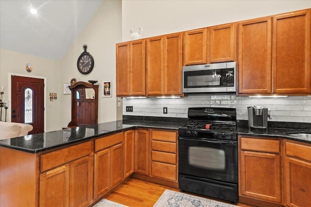 3 Pine Ln, Greenwood Lake, NY 10925 - kitchen with black range with gas stovetop, stainless steel microwave, a peninsula, vaulted ceiling, and backsplash
