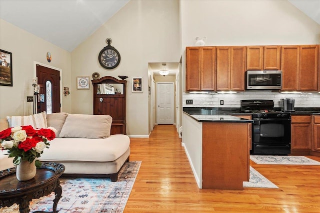 3 Pine Ln, Greenwood Lake, NY 10925 - kitchen featuring black gas stove, stainless steel microwave, high vaulted ceiling, light wood-style flooring, and dark countertops