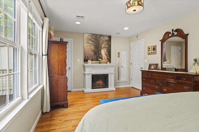 3 Pine Ln, Greenwood Lake, NY 10925 - bedroom featuring light wood-style flooring, multiple windows, baseboards, a glass covered fireplace, and recessed lighting