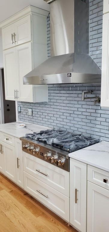 4 Coventry Ct, Wheatley Heights, NY 11798 - kitchen with wall chimney exhaust hood, stainless steel gas stovetop, decorative backsplash, and white cabinetry