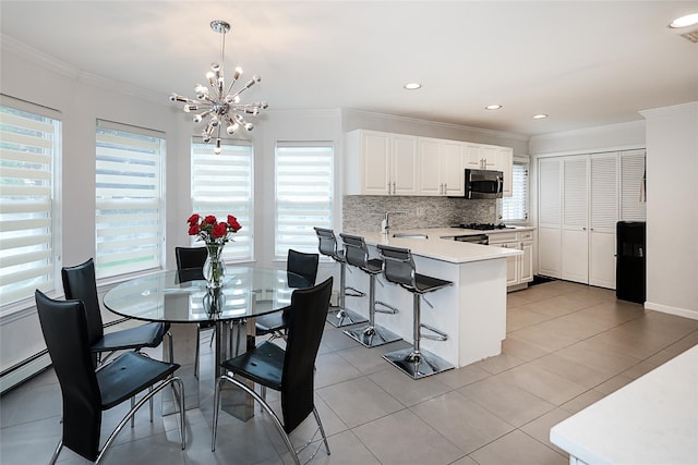 2448 6th Ave, East Meadow, NY 11554 - kitchen with stainless steel microwave, a peninsula, plenty of natural light, crown molding, and a chandelier