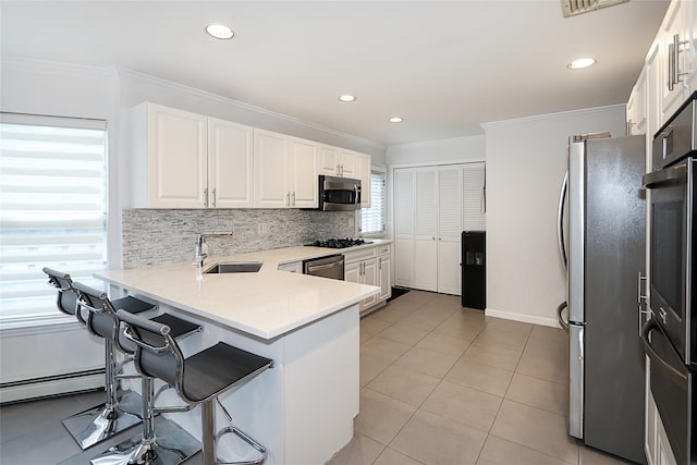 2448 6th Ave, East Meadow, NY 11554 - kitchen featuring appliances with stainless steel finishes, a sink, ornamental molding, tasteful backsplash, and white cabinets