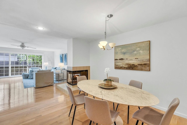 500 Meadow Ct Unit 28, Southold, NY 11971 - dining area featuring light wood-style flooring, a chandelier, a tile fireplace, a ceiling fan, and recessed lighting