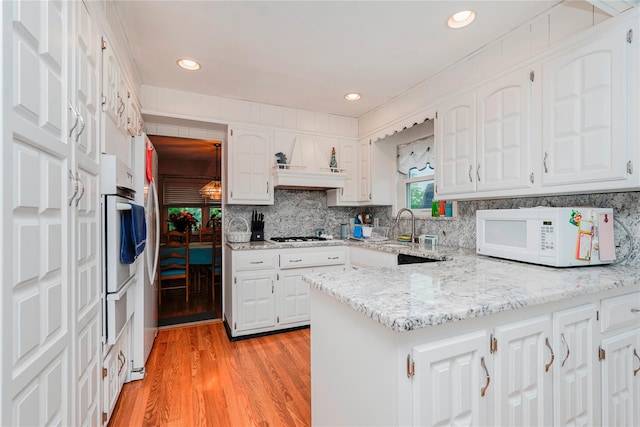 433 Arlene St, Staten Island, NY 10314 - kitchen featuring white appliances, a peninsula, white cabinets, light wood-style floors, and tasteful backsplash
