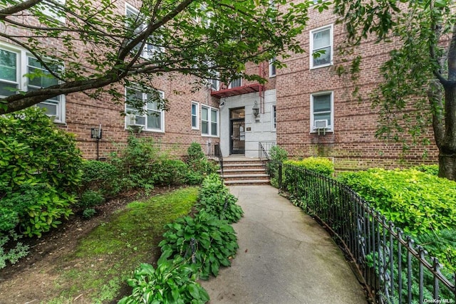 entrance to property featuring brick siding and fence
